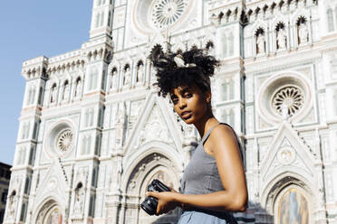 Porträt einer jungen Frau mit Kamera vor einer Kathedrale, Florenz, Italien - SODF00492