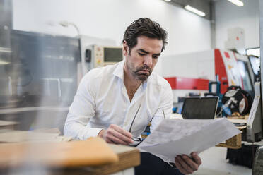 Geschäftsmann liest Papier in einer Fabrik - DIGF09035