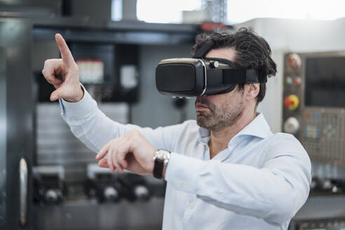 Businessman using VR glasses in a factory - DIGF09061