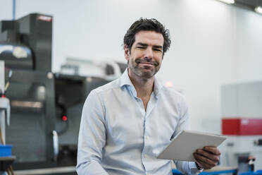 Portrait of a confident businessman holding tablet in a factory - DIGF09071