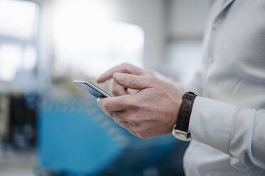 Close-up of businessman using cell phone in a factory - DIGF09076