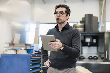 Geschäftsmann hält Tablet in einer Fabrik - DIGF09082