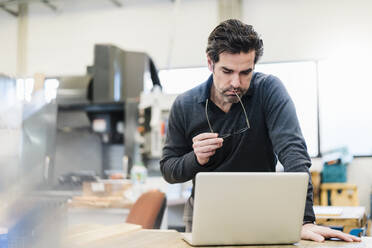 Geschäftsmann mit Laptop in einer Fabrik - DIGF09086