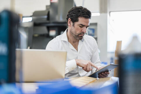 Geschäftsmann mit Tablet in einer Fabrik, lizenzfreies Stockfoto