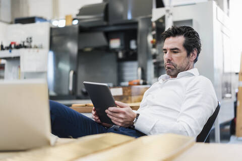 Geschäftsmann mit Tablet in einer Fabrik, lizenzfreies Stockfoto