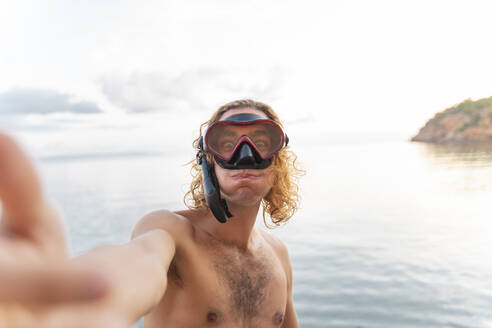 Young man with snorkel making a face on the beach - AFVF04982