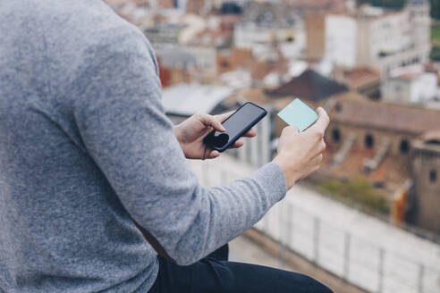 Nahaufnahme eines jungen Mannes, der in Lleida mit der Kreditkarte seines Mobiltelefons bezahlt - ACPF00651