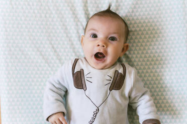 Porträt eines überraschten kleinen Mädchens mit applizierten Kopfhörern auf einem Pyjama - GEMF03397