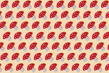 Red mushroom with white spots wooden toy in a row on yellow background - GEMF03401