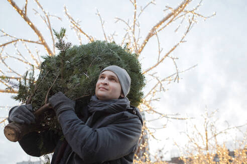 Junger Mann mit Tannenbaum auf der Schulter - EYAF00793