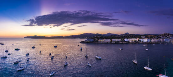 Spanien, Mallorca, Santa Ponsa, Luftpanorama von Booten, die in der violetten Abenddämmerung im Küstenwasser schwimmen, mit der Stadt im Hintergrund - AMF07691