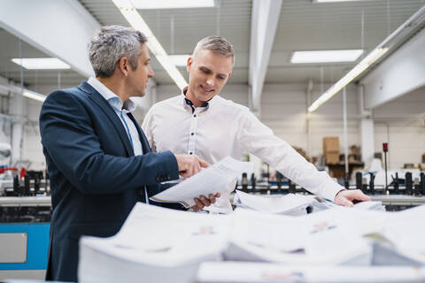 Zwei Geschäftsleute diskutieren über Papier in einer Fabrik, lizenzfreies Stockfoto