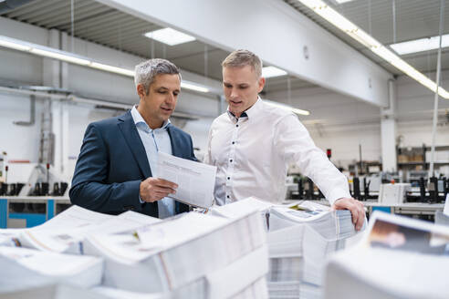 Zwei Geschäftsleute diskutieren über Papier in einer Fabrik - DIGF09133