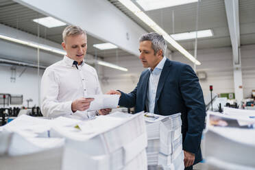 Zwei Geschäftsleute diskutieren über Papier in einer Fabrik - DIGF09134