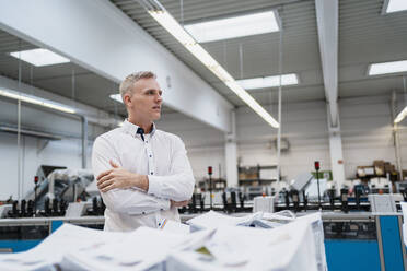 Mann im weißen Hemd in einer Fabrik, der sich umschaut - DIGF09138