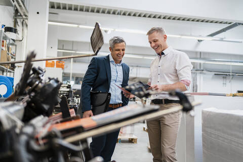 Zwei glückliche Geschäftsleute betrachten Ordner in einer Fabrik, lizenzfreies Stockfoto