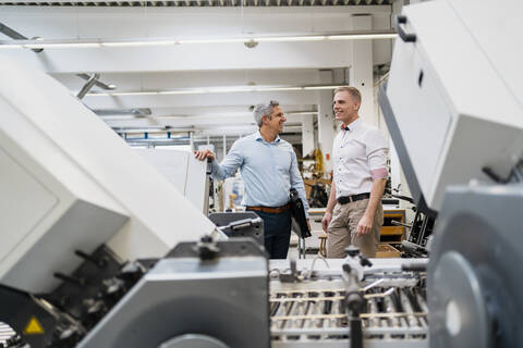 Zwei lächelnde Kollegen in einer Fabrik, lizenzfreies Stockfoto