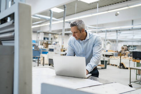 Geschäftsmann mit Laptop in einer Fabrik - DIGF09159