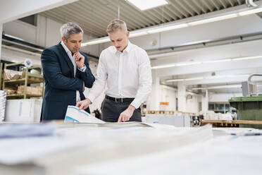 Zwei Geschäftsleute diskutieren über Papier in einer Fabrik - DIGF09173