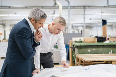 Zwei Geschäftsleute diskutieren über Papier in einer Fabrik - DIGF09175