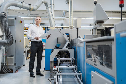 Geschäftsmann hält Papier in einer Fabrik - DIGF09183