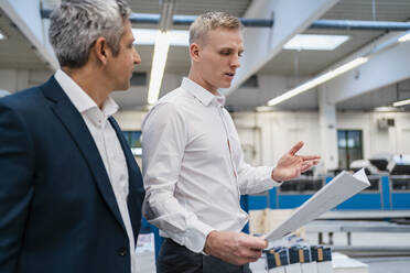 Two businessmen with paper talking in a factory - DIGF09187