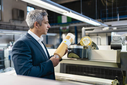 Businessman in a factory examining product - DIGF09202