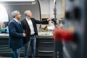 Two businessmen at a machine in a factory - DIGF09209