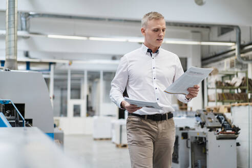 Geschäftsmann hält Papier in einer Fabrik - DIGF09231