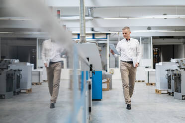 Businessman holding paper in a factory - DIGF09232