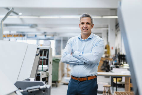 Porträt eines selbstbewussten Geschäftsmannes in einer Fabrik, lizenzfreies Stockfoto