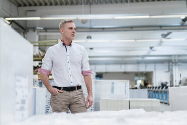 Mann im weißen Hemd in einer Fabrik, der sich umschaut - DIGF09242
