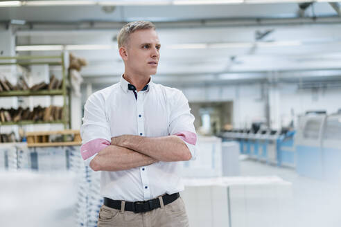 Mann im weißen Hemd in einer Fabrik, der sich umschaut - DIGF09243