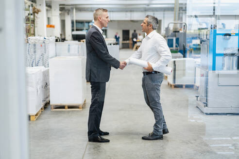 Two businessmen shaking hands in a factory - DIGF09259