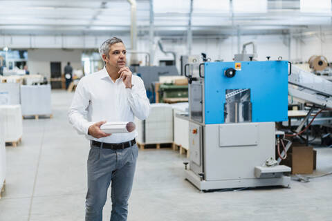 Mann im weißen Hemd in einer Fabrik, der sich umschaut, lizenzfreies Stockfoto