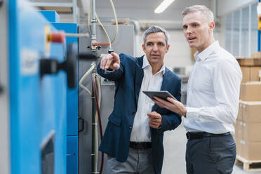 Two businessmen with tablet talking in a factory - DIGF09278