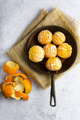 Freshly peeled mandarines on frying pan - GIOF07933