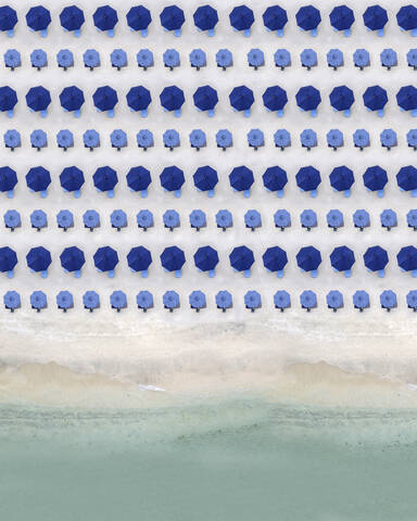 Luftaufnahme von Reihen blauer Sonnenschirme, die am Sandstrand stehen, lizenzfreies Stockfoto