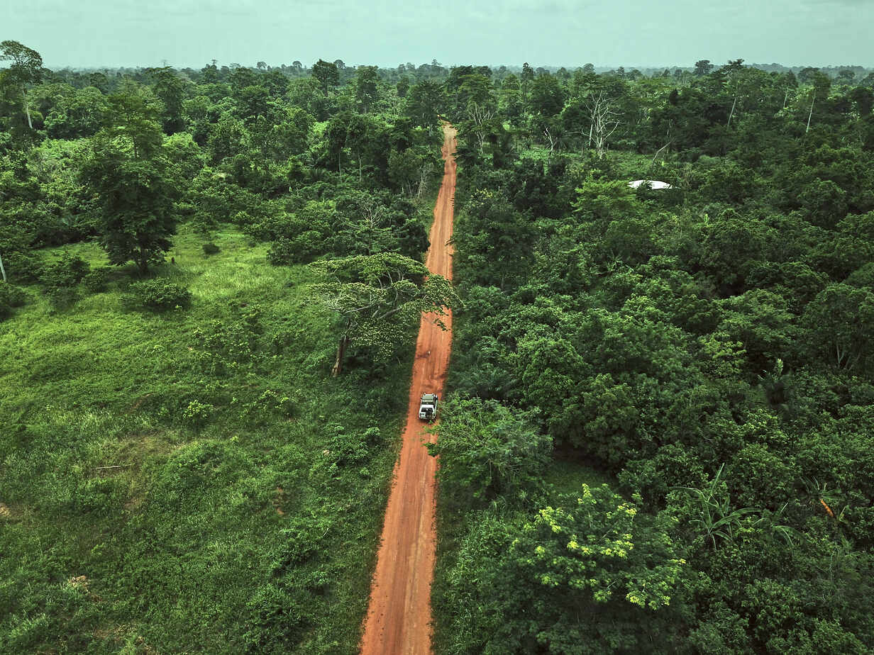 Ivory Coast, Korhogo, Aerial view of 4x4 car driving along dirt road ...