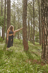 Barefoot young woman doing stretching exercise in the woods - VEGF01306