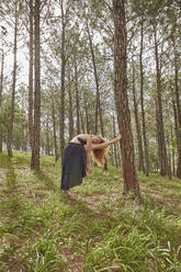 Barfüßige junge Frau bei Dehnungsübungen im Wald - VEGF01308