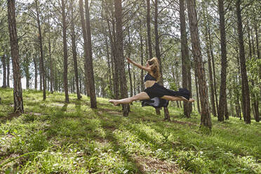 Barefoot young woman jumping in the air in the woods - VEGF01311