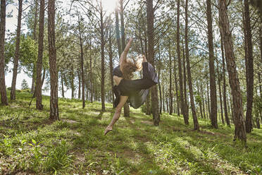 Junge Frau springt barfuß im Wald in die Luft - VEGF01312