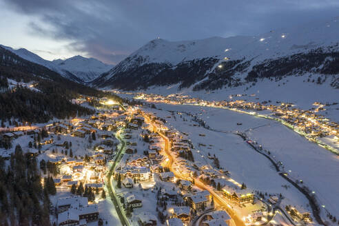 Italien, Provinz Sondrio, Livigno, Luftaufnahme einer beleuchteten Stadt in den italienischen Alpen in der Abenddämmerung - WPEF02421