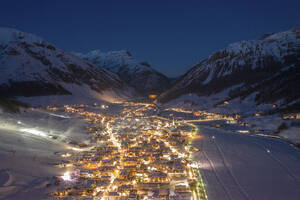 Italien, Provinz Sondrio, Livigno, Luftaufnahme einer beleuchteten Stadt in den italienischen Alpen in der Abenddämmerung - WPEF02426