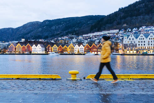 Frau mit gelber Jacke und Spaziergang am Hafen in Bergen, Norwegen - DGOF00005