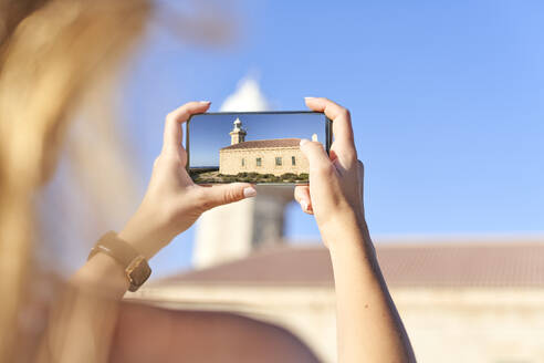 Junge Frau beim Fotografieren des Leuchtturms von Punta Nati, Menorca, Spanien - EPF00660
