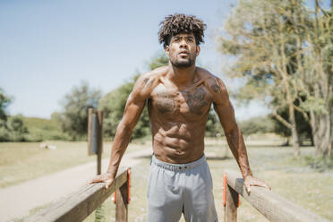 Junger Mann beim Training am Barren im Park - FBAF01194