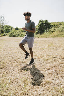 Junger Mann beim Training joggt in einem Park auf der Stelle - FBAF01206