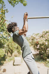 Young man during workout on a bar in a park - FBAF01210